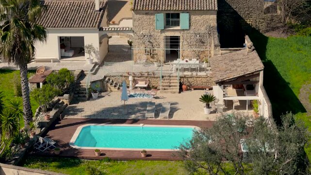 Aerial drone descends over Proven&ccedil;al stone mas with turquoise swimming pool