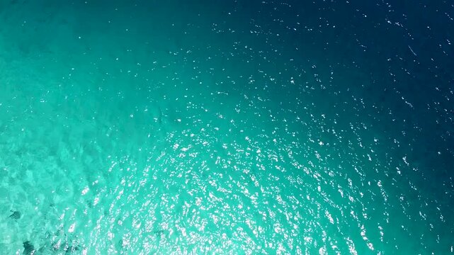 Aerial view above coral reef in crystal clear turquoise ocean into deep blue water of coral triangle region of Timor-Leste