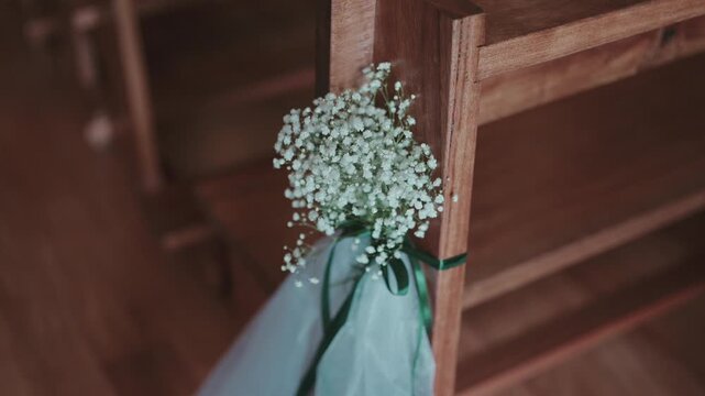 Gypsophila flowers tied with ribbon decorating wooden church bench at wedding