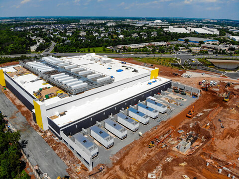 Aerial view of a large data center construction site with industrial equipment, red soil, and surrounding suburban infrastructure in Ashburn, Virginia, United States.
