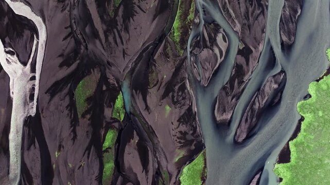Aerial view of braided glacial river channels winding through dark volcanic sand in Iceland