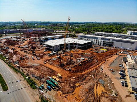 Aerial view of a large construction site featuring cranes, heavy machinery, and a building structure under development in Ashburn, Virginia, United States.