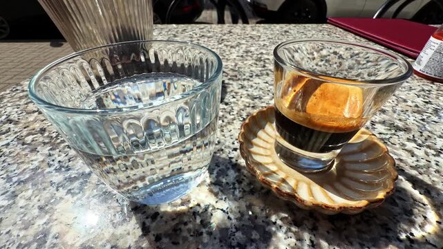 Pour over coffee brewing setup with glass dripper and espresso cup on granite countertop in natural light