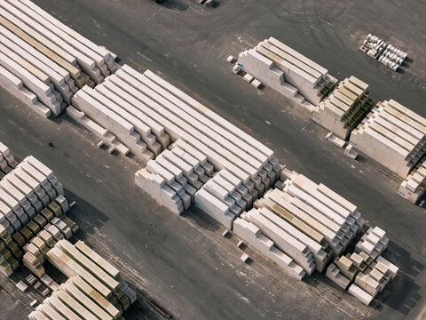 Aerial view of stacked concrete blocks in a storage yard with rows of construction materials on asphalt ground in Dulmen, North Rhine-Westphalia, Germany.