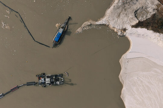Aerial view of industrial dredging equipment operating in a murky water basin with sandy banks and sediment deposits in Dulmen, North Rhine-Westphalia, Germany.