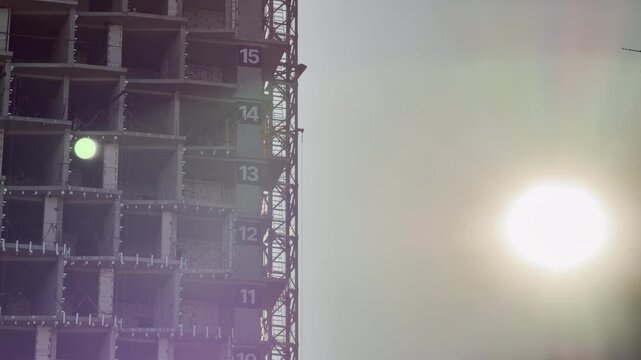 A towering concrete frame rises toward the sun in Simferopol, Crimea. Numbered floors mark its steady, ambitious climb, evoking a feeling of hopeful progress and urban growth.