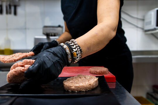 Chef hands forming raw burger patties in restaurant kitchen for gourmet meal preparation