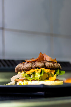 Gourmet beef burger with bacon, cheese, and fresh vegetables on a bun