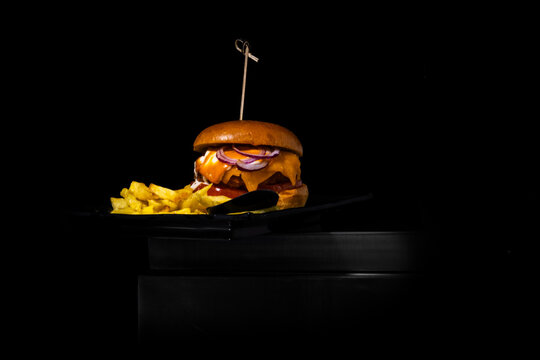 Gourmet cheeseburger with french fries on a black plate, reflecting a premium dining experience