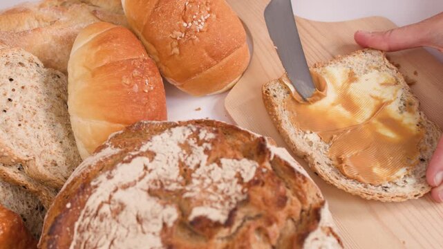 Spreading Creamy Peanut Butter on Multigrain Bread with Assorted Loaves