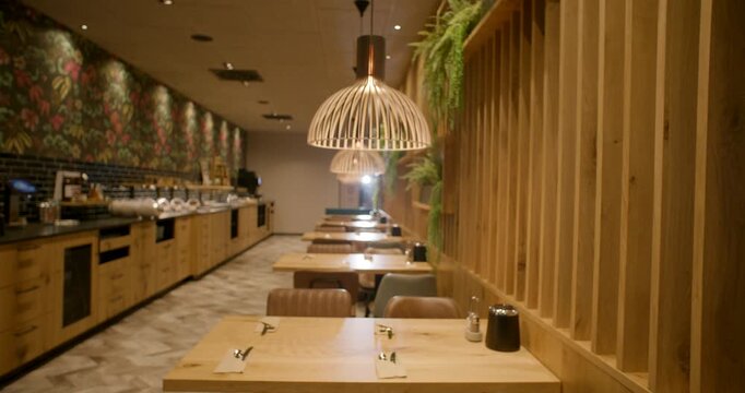 Interior view of an empty modern restaurant with wooden tables and unique dome pendant lamps