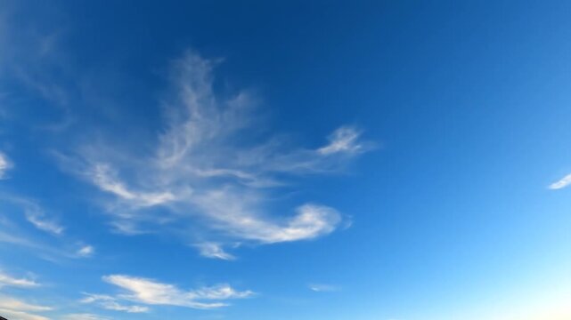 Beautiful wispy white clouds drift across a vibrant blue sky
