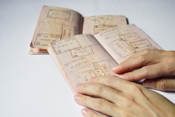 Fototapeta premium Close-up of hands holding passport pages filled with dated entry stamps from international journeys. Depicts travel verification, immigration record checking, and international mobility documentation.