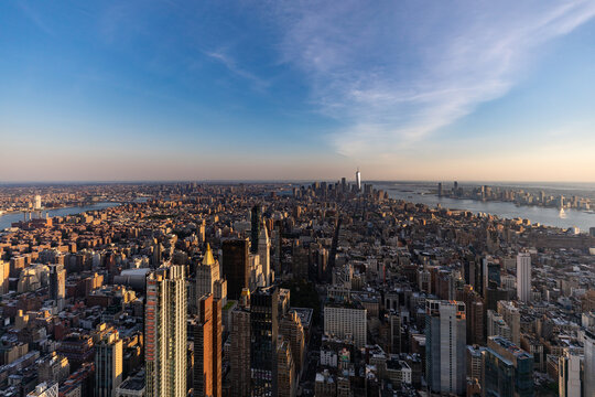 View of the expansive New York City skyline at sunset, featuring iconic skyscrapers, dense urban architecture, and the Hudson River in New York, New York, United States.