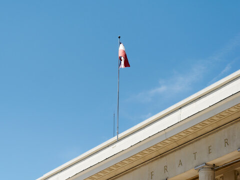 Drapeau fran&ccedil;ais flottant au sommet d&rsquo;un b&acirc;timent public sous un ciel bleu d&eacute;gag&eacute;