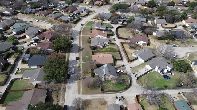 Residential block southeast US 75 near Premier Dr features aligned homes, narrow setbacks, visible backyard elements along straight connecting streets. Muted shingles, dormant trees, Plano, TX