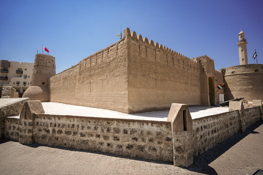 View of the historic Al Fahidi Fort with its traditional stone walls, defensive towers, and a minaret under a clear blue sky in Dubai, Dubai, United Arab Emirates.