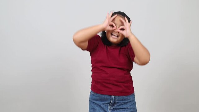 Asian child doing funny faces making with finger glasses shape like glasses looking through binoculars