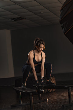 Fit young woman trains with a kettlebell, showcasing power and endurance in a stylish fitness studio. The gym environment highlights her dedication to a healthy and active lifestyle