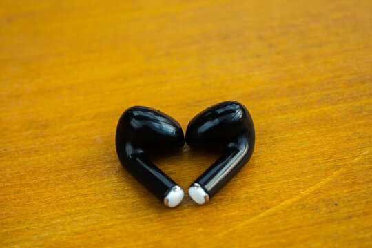 Wireless Black Earbuds on Wooden Surface with Minimal Background