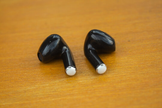 Wireless Black Earbuds on Wooden Surface with Minimal Background