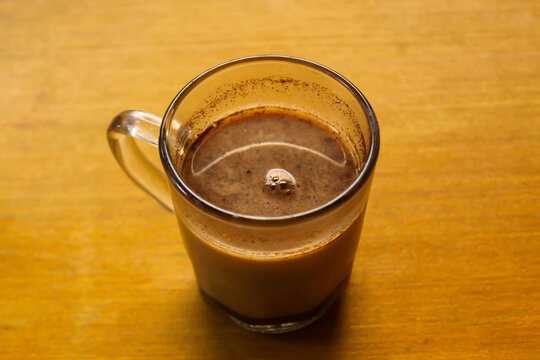 Cup of Hot Milk Coffee in Glass Mug on Wooden Table with Copy Space