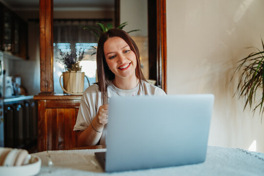 Young woman remotely working on laptop from home