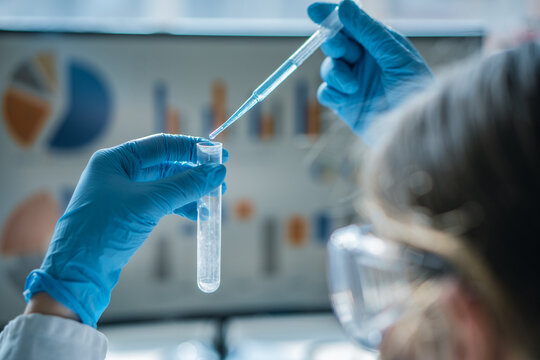 Close up of a researcher performing an experiment with a pipette and test tube, focusing on precision and safety. Laboratory environment highlights innovation and scientific discovery