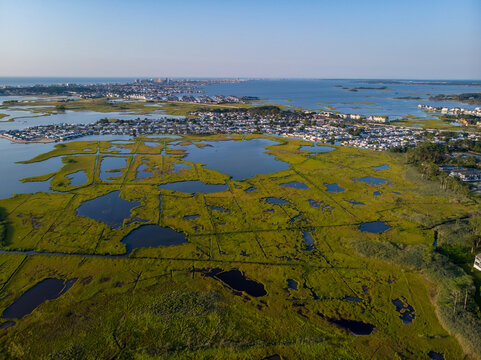 Ocean City, Maryland, United States - 28 July 2019: Aerial view of the coastal marshlands and wetlands with residential developments in the distance under a clear sky.