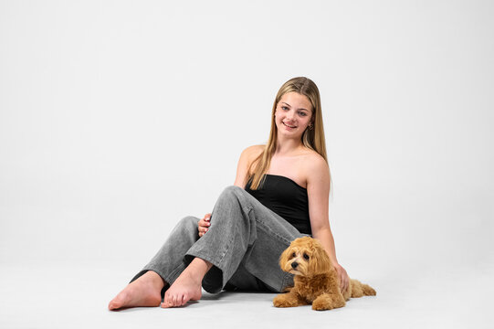 Studio portrait series of a smiling teenage girl interacting with her small fluffy puppy in a minimalist white studio. Authentic friendship between young owner and pet, emotional connection, care, aff