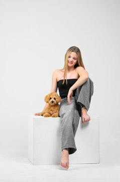 Studio portrait series of a smiling teenage girl interacting with her small fluffy puppy in a minimalist white studio. Authentic friendship between young owner and pet, emotional connection, care, aff