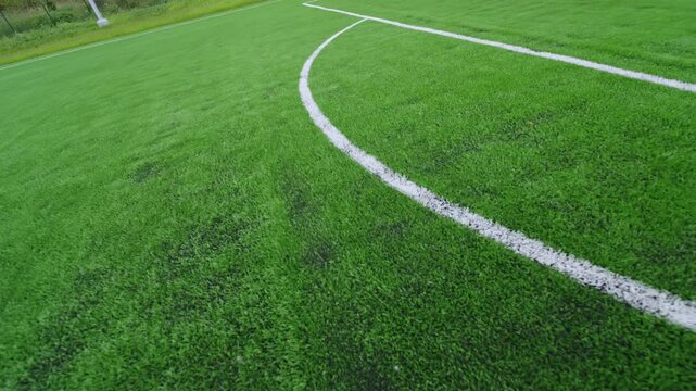 Artificial grass field features curved lines for sports markings. Synthetic turf provides durable surface for football and soccer