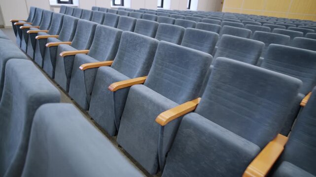 Lecture room shows upholstered velvet theater chairs arranged in rows. Institutional design establishes comfortable environment for students