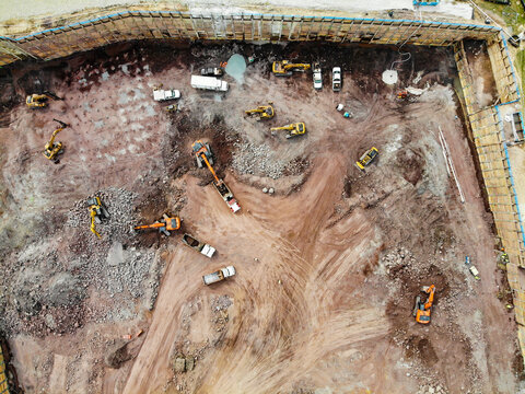 Reston, Virginia, United States - 12 March 2019: Aerial view of a construction site with excavators, dump trucks, and piles of earth within a fenced excavation area.