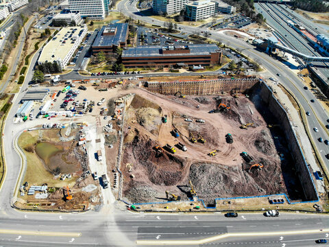 Reston, United States - 12 March 2019: Aerial view of a large construction site with excavators and earthmoving equipment operating within a deep excavation pit near urban roads.