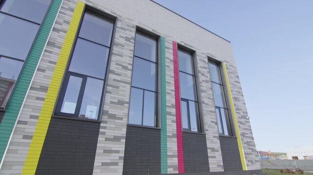 Educational facility architecture features bright panels on tiled wall surface. Modest design provides highly professional look for campus