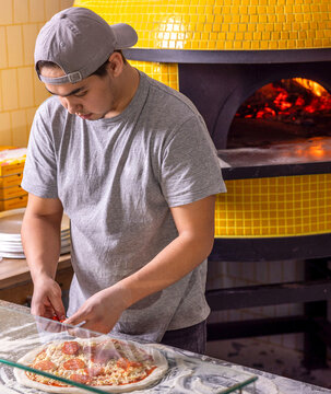  heese on pizza dough with tomato sauce. Process of making pizzas, pepperoni, salami. Raw pizza ingredients on table