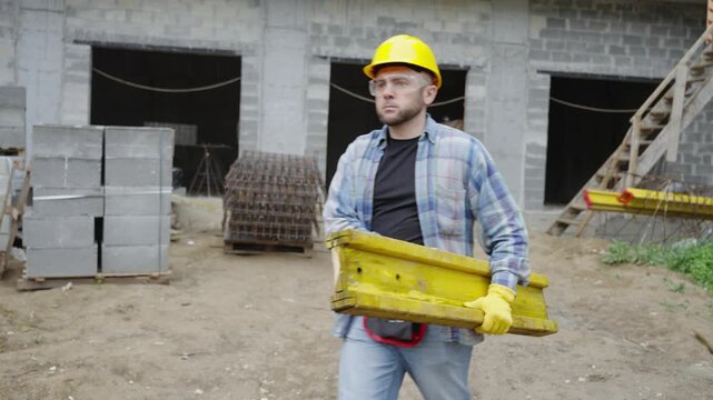 Construction worker carrying heavy formwork beam