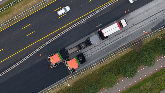 Bunnik, Utrecht, Netherlands - 16 June 2026: Aerial view of asphalt paving machines laying new surface on a highway, with workers in high-visibility vests and traffic nearby.