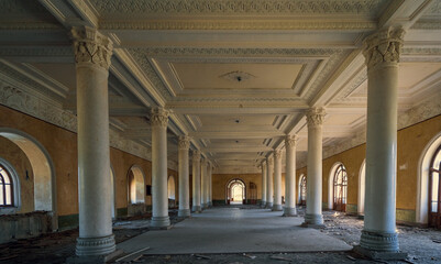 Naklejka premium Abandoned neoclassical hall with ornate columns and arched windows, historic architecture decay, urban exploration, restoration concept.