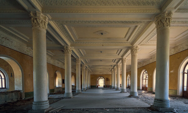Abandoned neoclassical hall with ornate columns and arched windows, historic architecture decay, urban exploration, restoration concept.