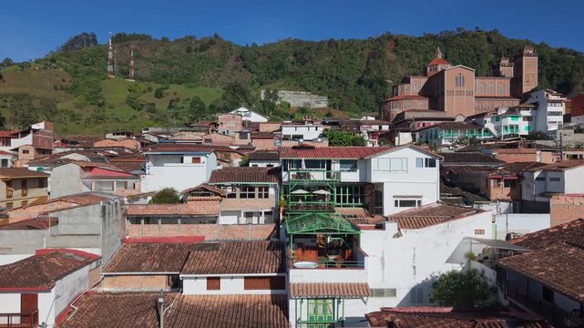 Aerial view over Jerico rooftops with large church and lush green hills in background