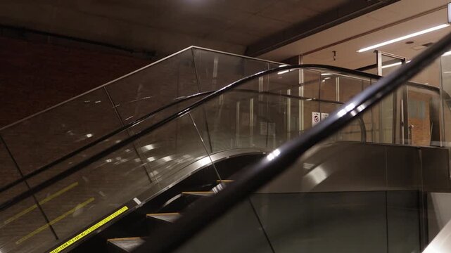 Empty moving escalator with glass panels and yellow safety strips inside modern Japanese subway station