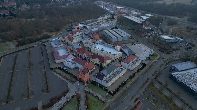 A large shopping outlet center with multiple buildings, retail stores, and an empty parking lot. Perfect aerial view top down drone view