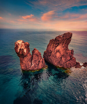 Fantastic morning view from flying drone of Red Rocks cliifs on Gli Scogli Rossi Faraglioni location. Spectacular summer sunrise on Sardinia island, Italy, Europe. Beauty of nature concept background.