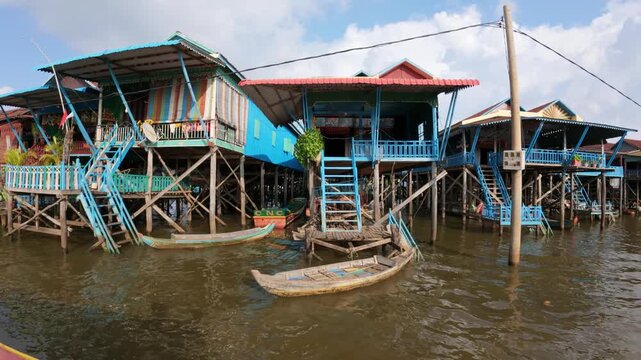 View of stilt houses on the water with wooden walkways and vibrant structures in the floating village Kampong Khleang, Siem Reap, Cambodia.