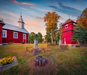 Wonderful evening view of red wooden St. Onos Catholic church. Nice autumn sunset on Duokiskis village, Rokiskis District Municipality, Latvia, Europe. Traveling concept background. © Andrew Mayovskyy