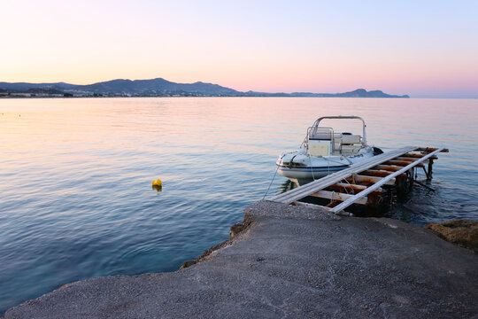 small boat alongside a stone pier in the evening