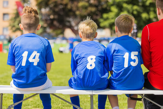 Youth Soccer Substitutes on Bench: Kids in Blue Jerseys Watching Football Match from Sideline