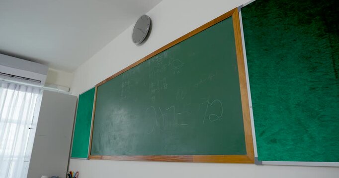 Slow motion camera pans across elementary classroom chalkboard with lesson notes, back to school first day scene, primary education setting ready for teacher instruction and student participation